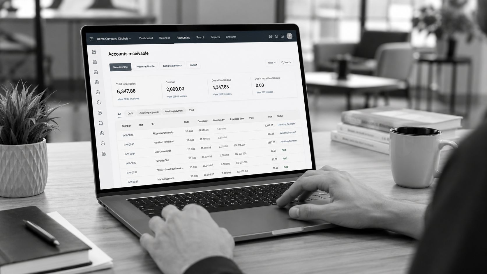 A professional working on a laptop displaying an accounts receivable dashboard in an office setting.